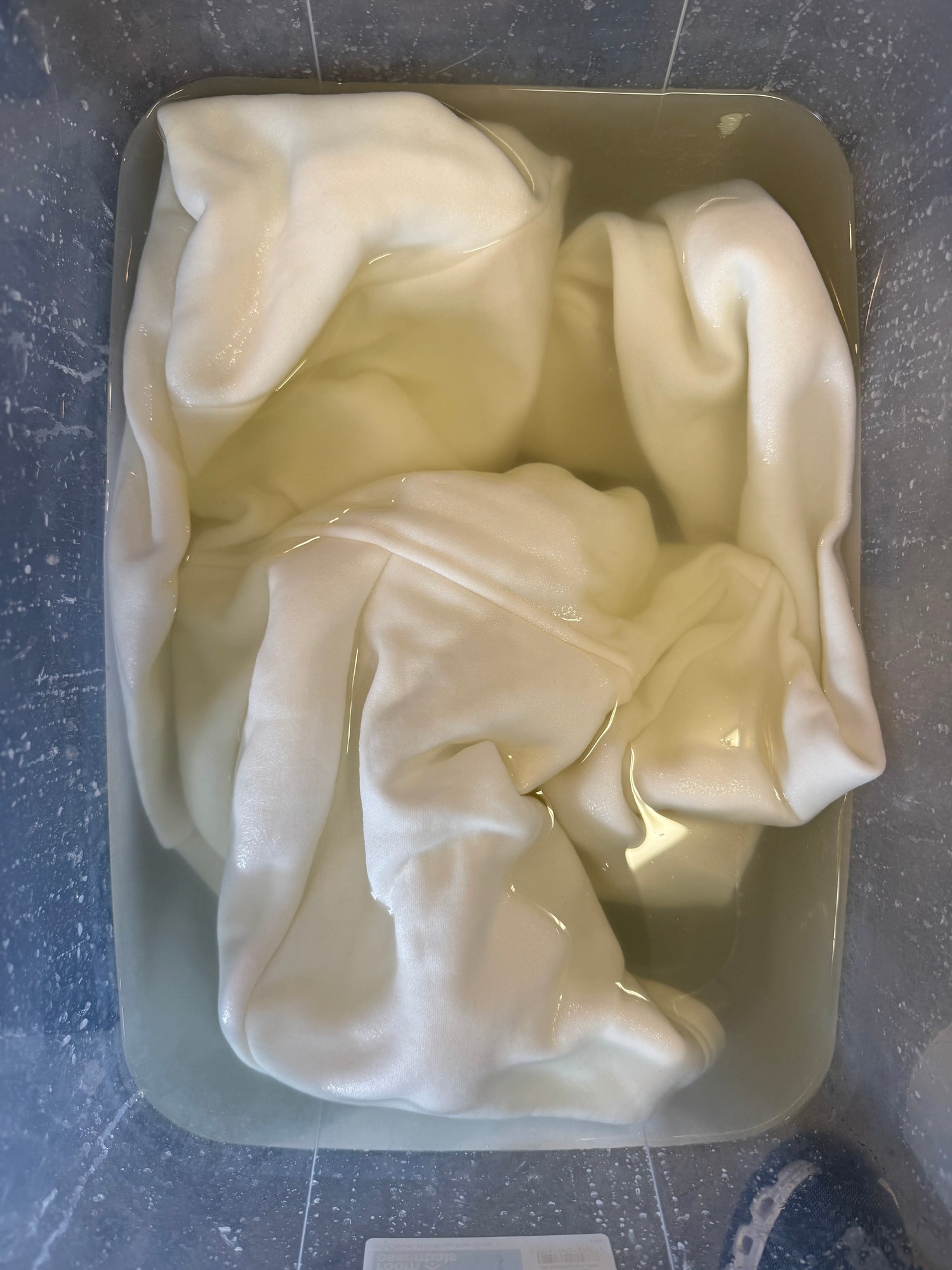 White blank apparel soaking in soda ash solution before ice dyeing at OB Tie Dye