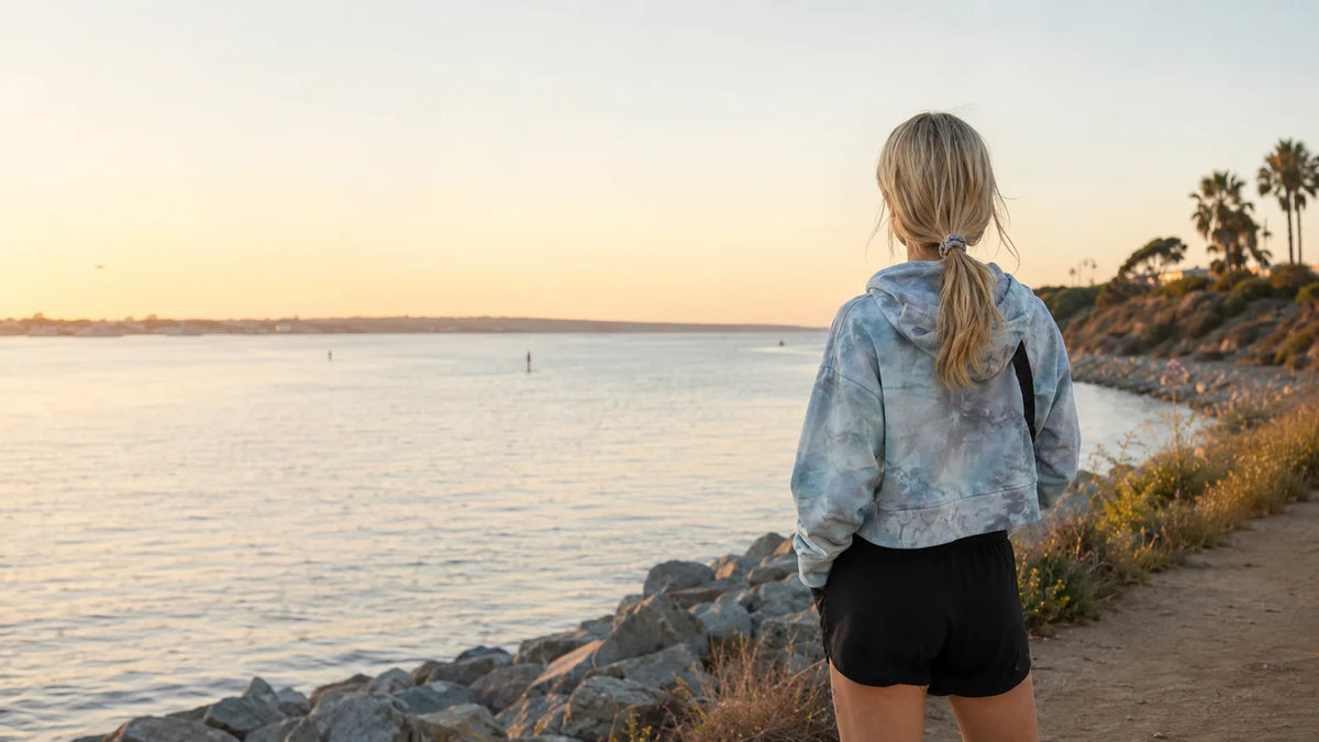 OB Tie Dye founder Jamie overlooking the San Diego coast in a one-of-one muted blue ice-dyed cropped hoodie.