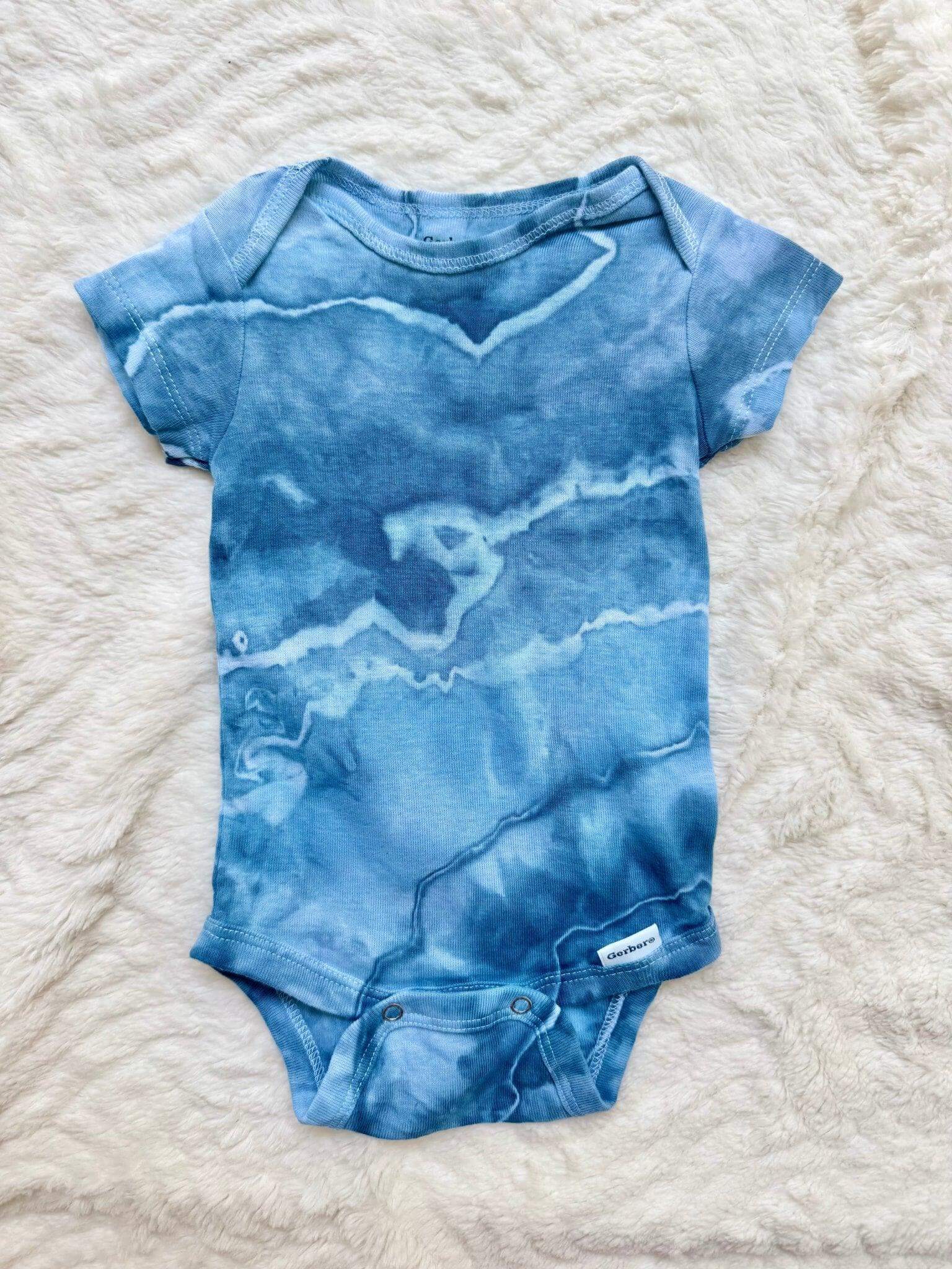 Blue ice-dye baby onesie on a textured white surface
