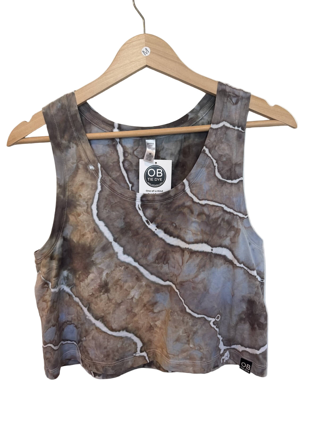 Marbled patterned tank greay, brown, blue and white top on a hanger with a brand tag against a white wall.
