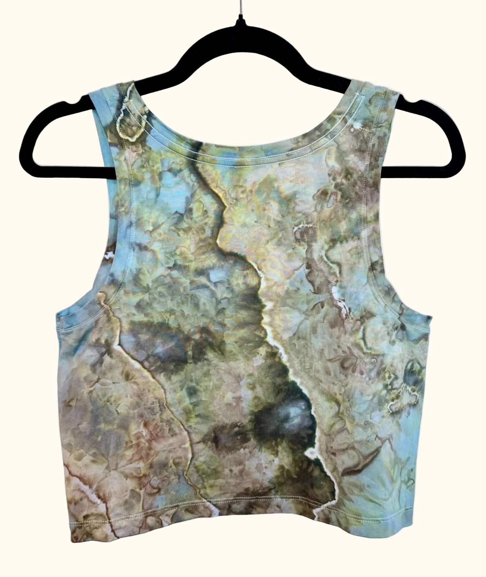 Back view of blue, green and earthy brown hand ice-dyed women’s crop tank on hanger