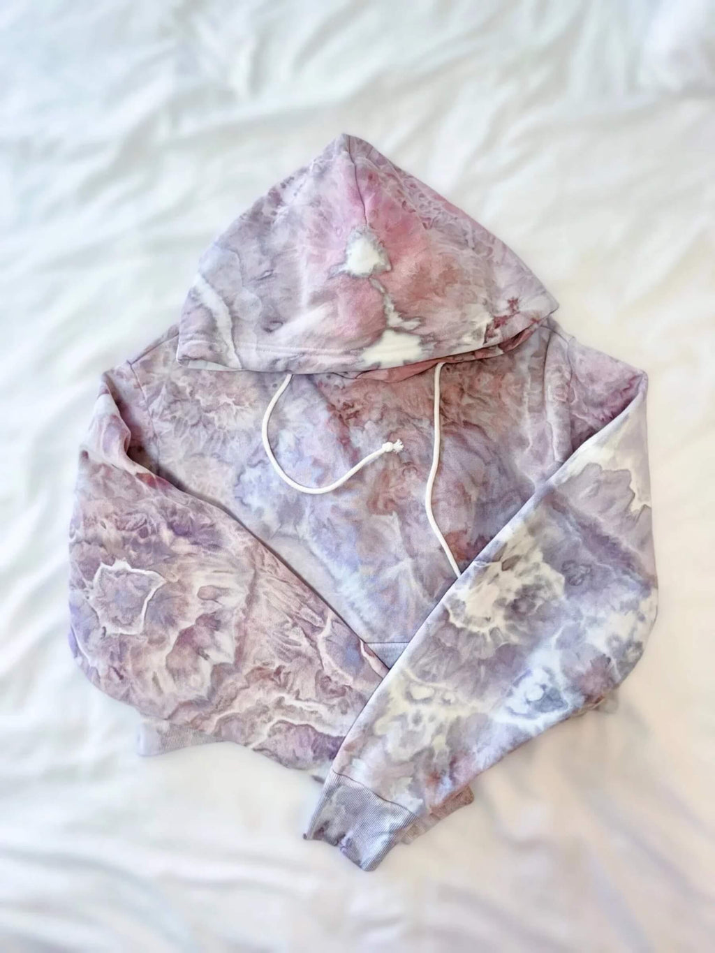 Folded pink and lavender cropped hoodie on a white surface