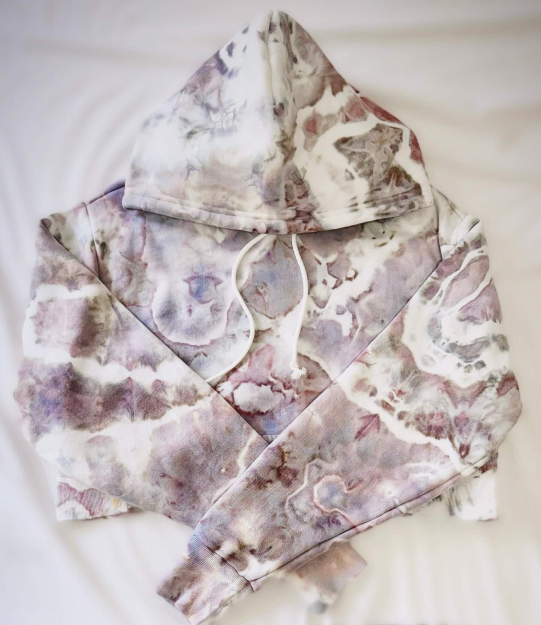 Marbled ice dyed white and purple cropped hoodie on a white background
