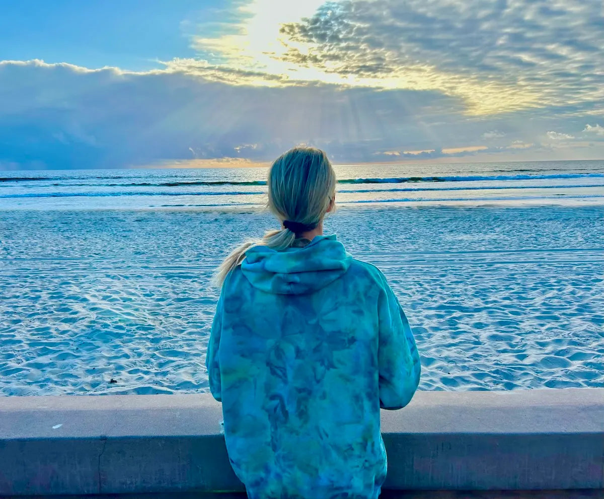 OB Tie Dye founder Jamie in a hand ice dyed hoodie looking at the ocean in San Diego during sunset