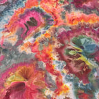 Close up of colorful ice dye beach towel with pink, orange, and green hues.