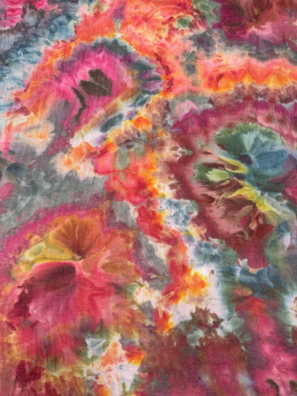Close up of colorful ice dye beach towel with pink, orange, and green hues.
