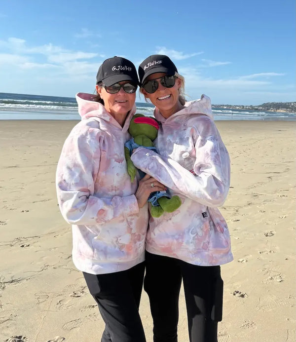 Two women on the beach wearing Shell Pink hand ice-dyed hoodies by OB Tie Dye