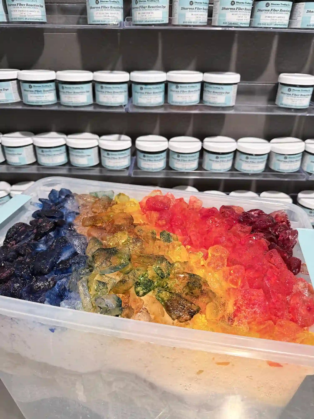 Ice dye process showing colorful dye-covered ice in the OB Tie Dye studio with Dharma dye jars in the background.