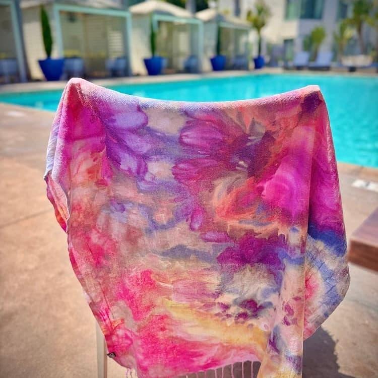 Hand ice-dyed Turkish towel by OB Tie Dye with soft pink, purple, and sand tones, photographed poolside in Southern California.