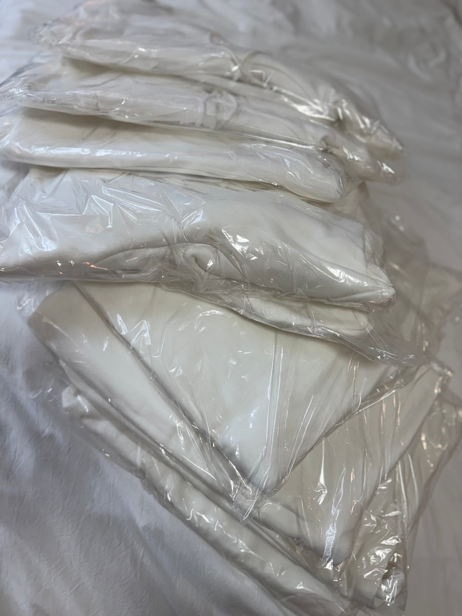 Stack of premium white blank apparel for OB Tie Dye, packaged and ready for ice dyeing