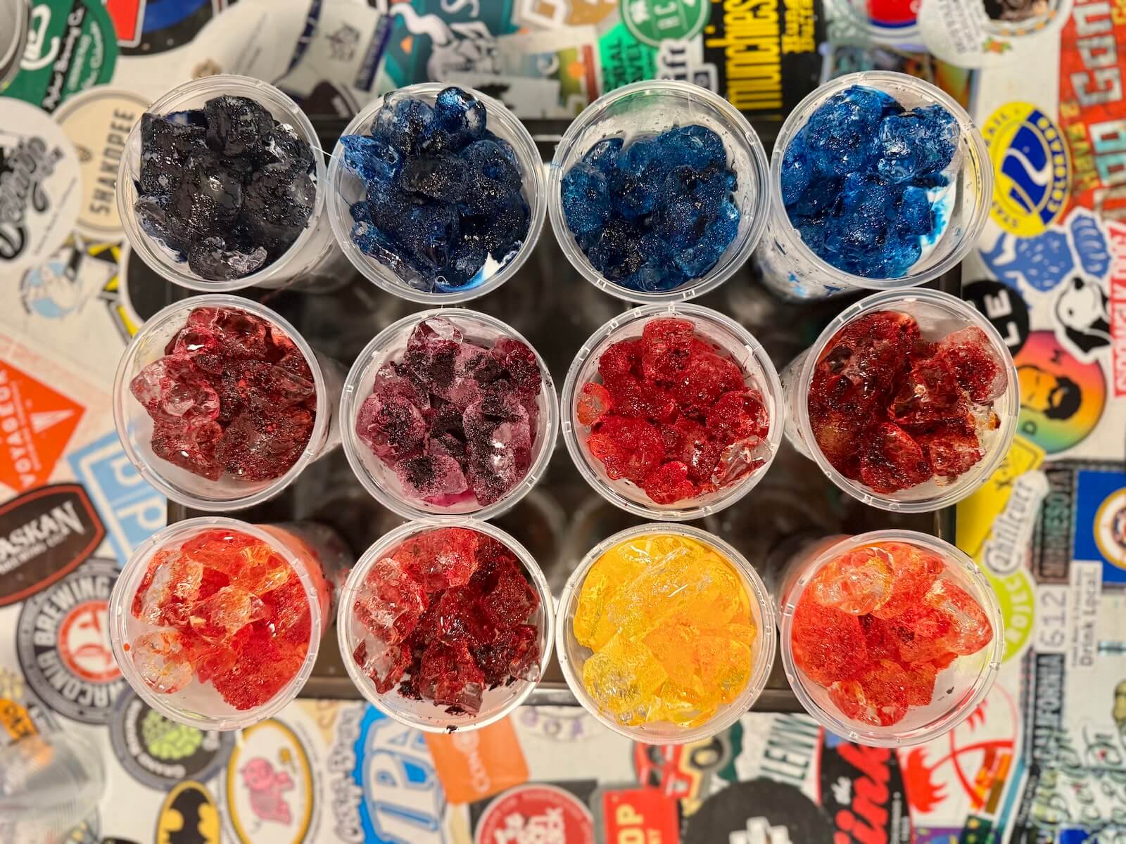 Assorted colored ice dye batches in small containers for swatches on a colorful background